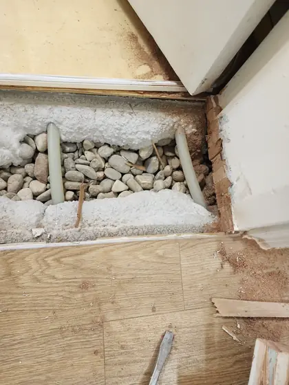 문턱 제거 미장 — 문지방 아래 자갈과 배관
