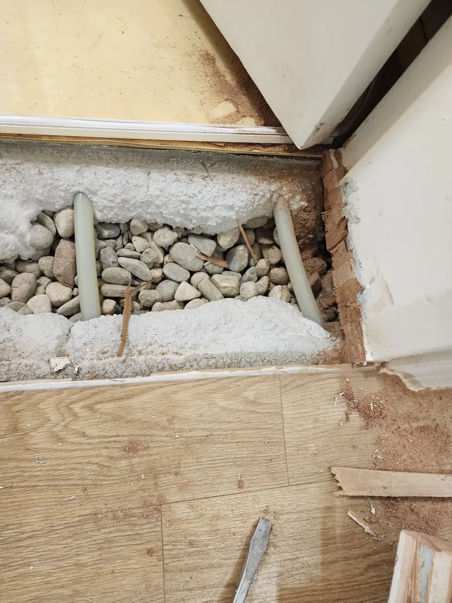 문턱 제거 미장 — 문지방 아래 자갈과 배관